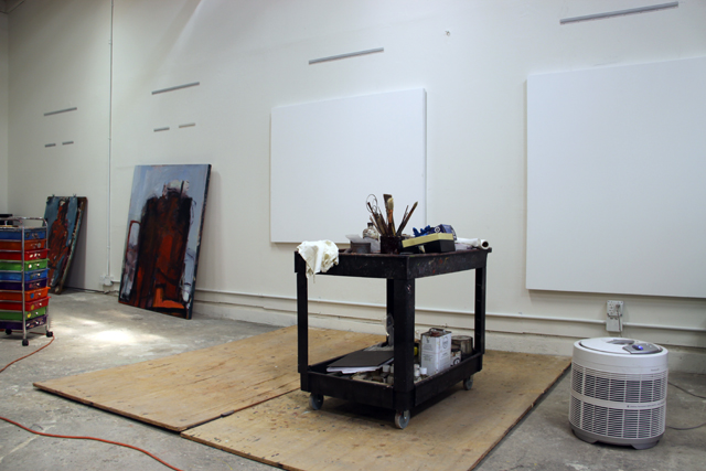 the studio of Barbara Downs, with several large blank canvases hanging on the wall